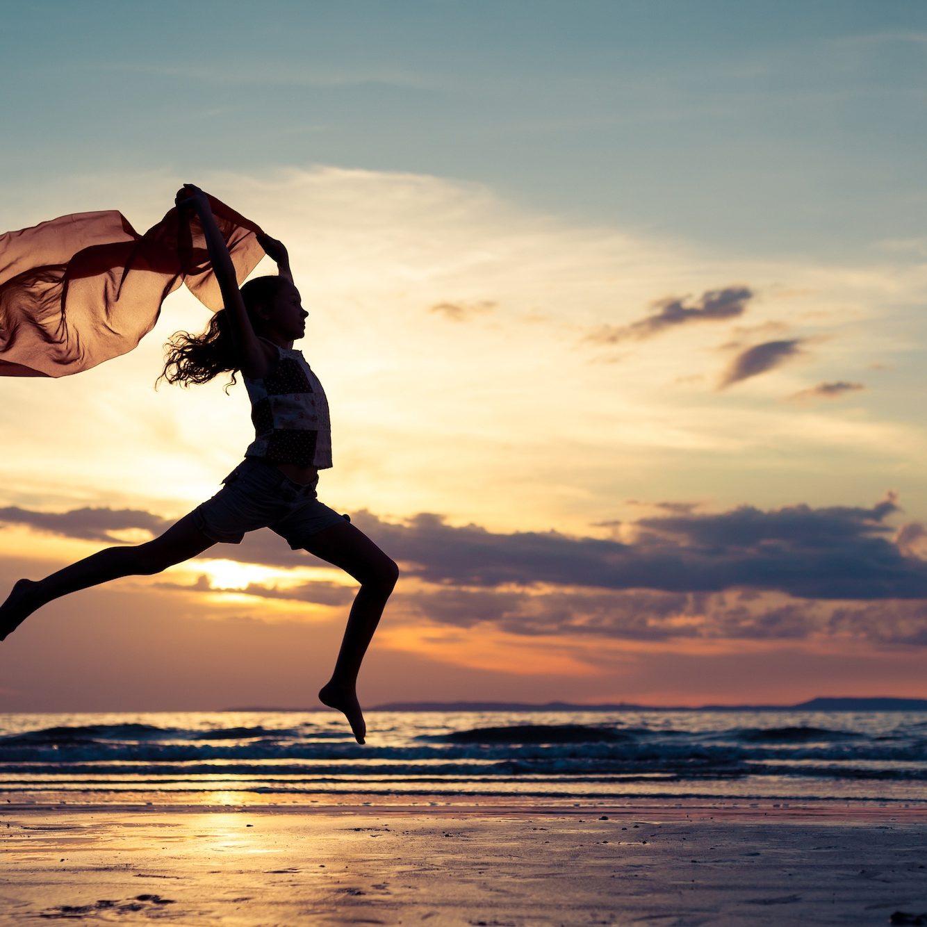 Happy teen girl jumping on the beach at the sunset timeHappy girl jumping on the beach at the sunset time